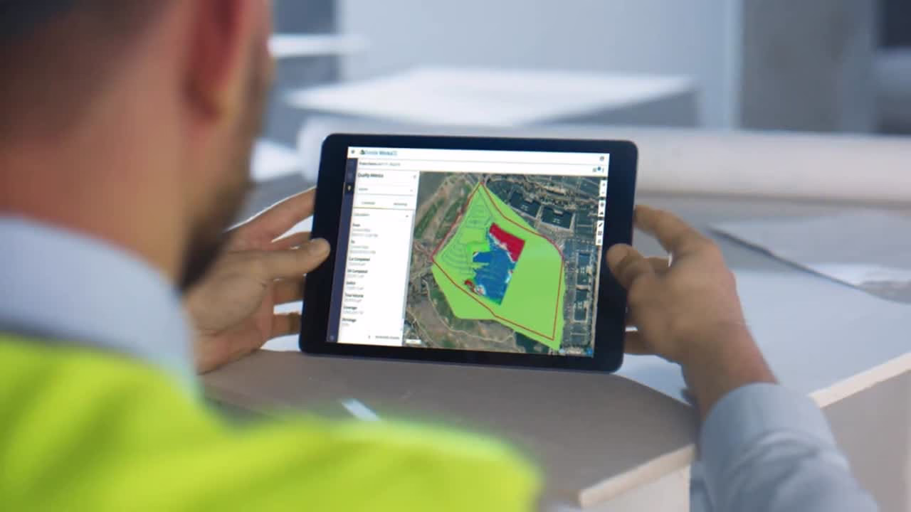 Construction supervisor using Trimble Siteworks software on a tablet inside a vehicle to manage 3D models and survey data in the field.